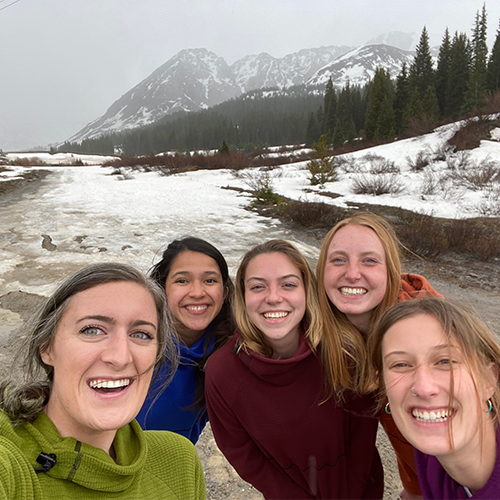 five women together in a snowy mountain setting