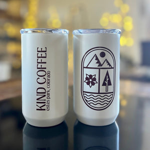 two of the same mugs side by side, the back says Kind Coffee and the front has a modern mountain, flower, tree, river design 
