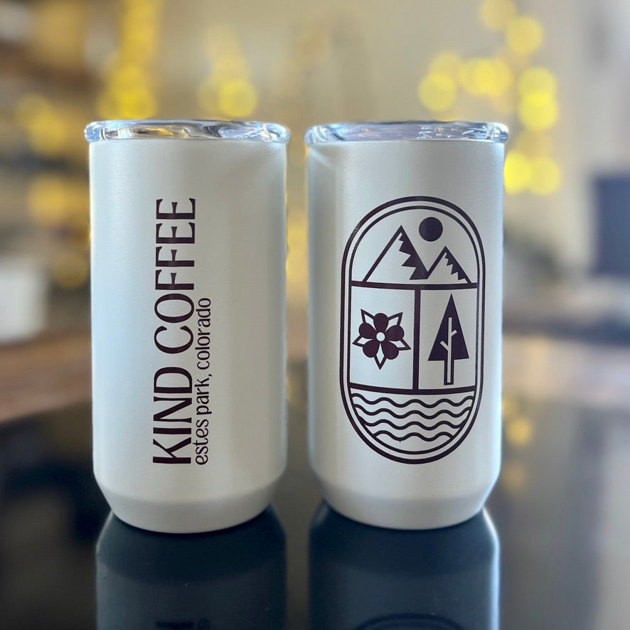 two of the same mugs side by side, the back says Kind Coffee and the front has a modern mountain, flower, tree, river design 