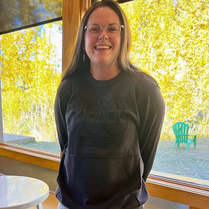 Smiling girl in a dark grey sweatshirt with fall leaves in the background