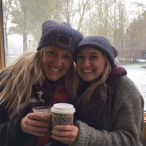 two women dressed warmly enjoying kind coffee drinks