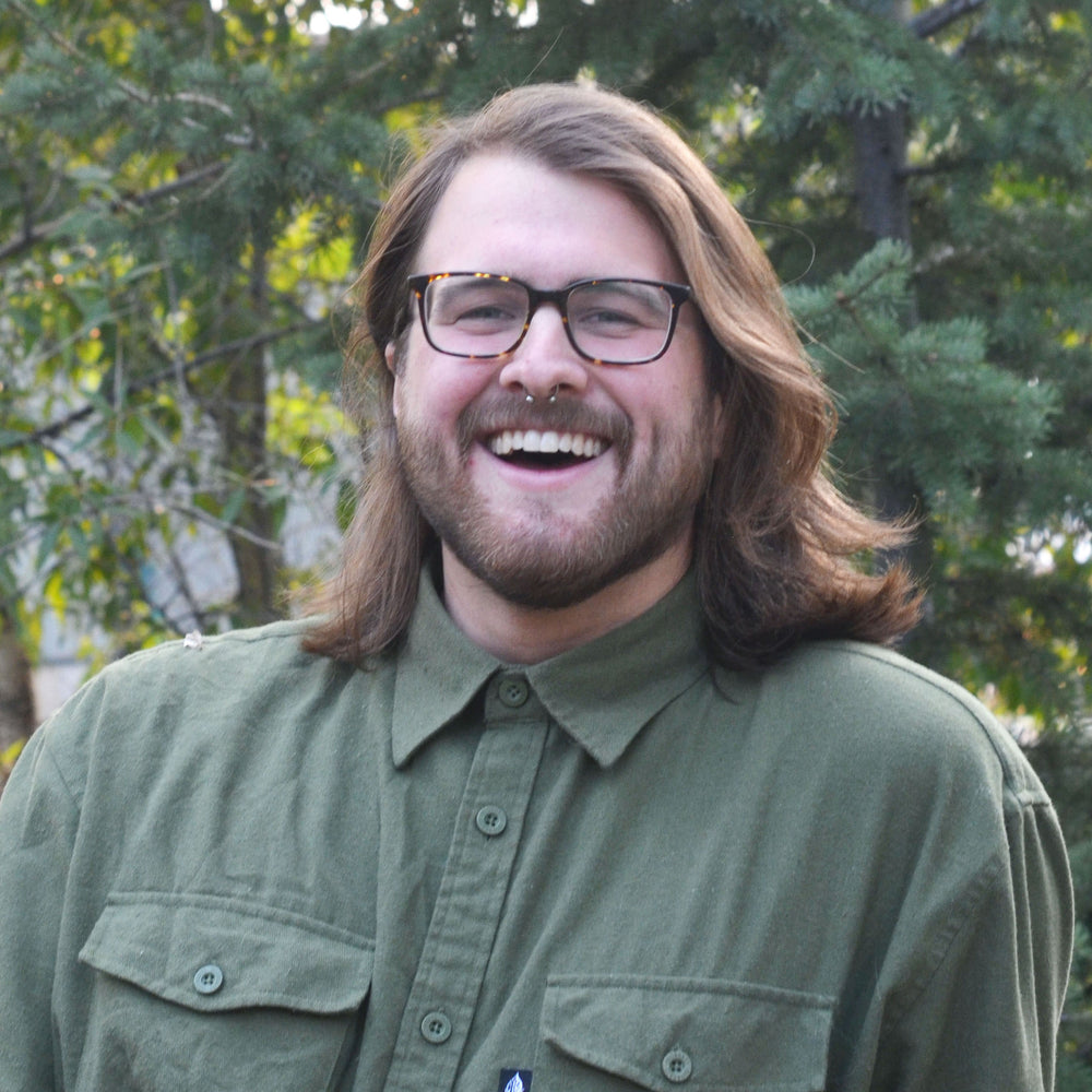 bearded man with long hair smiling outside