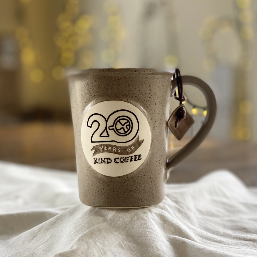 Sandstone ceramic mug with "20 Years of Kind Coffee" on a white cloth