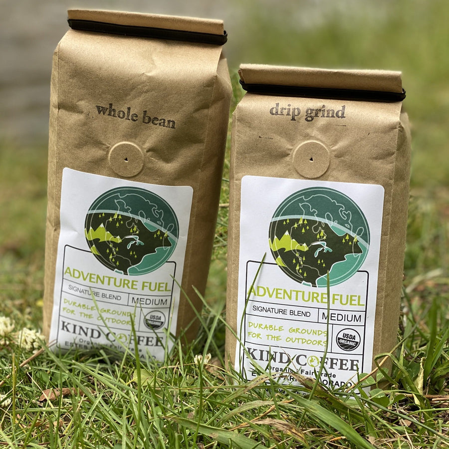 Two 1 lb bags of the Adventure Fuel Roast, one whole bean and one drip grind, sitting in the grass.